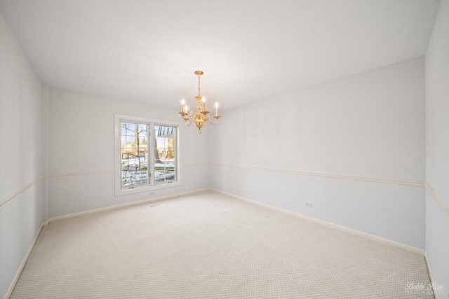 carpeted empty room featuring a chandelier