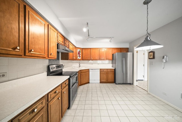 kitchen with appliances with stainless steel finishes, sink, decorative backsplash, hanging light fixtures, and light tile patterned floors