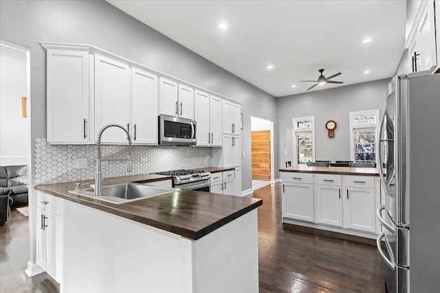 kitchen with sink, decorative backsplash, stainless steel appliances, and white cabinets