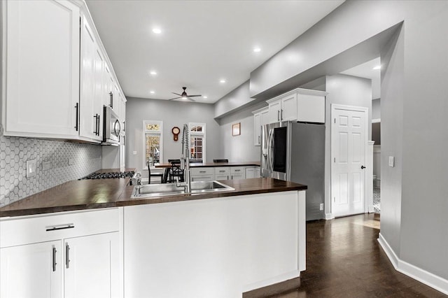 kitchen with stainless steel appliances, sink, white cabinets, and kitchen peninsula