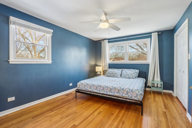 bedroom with ceiling fan, multiple windows, and light hardwood / wood-style flooring