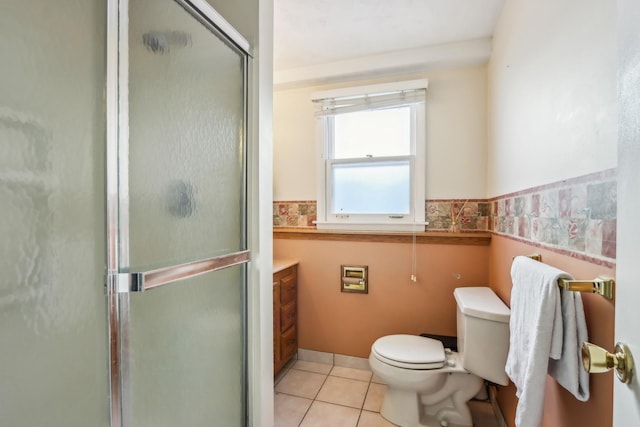 bathroom featuring toilet, vanity, a shower with door, and tile patterned flooring