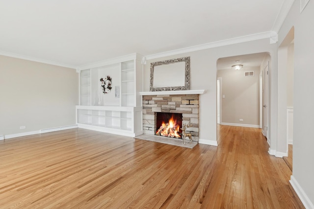 unfurnished living room with light hardwood / wood-style flooring, built in shelves, a stone fireplace, and ornamental molding