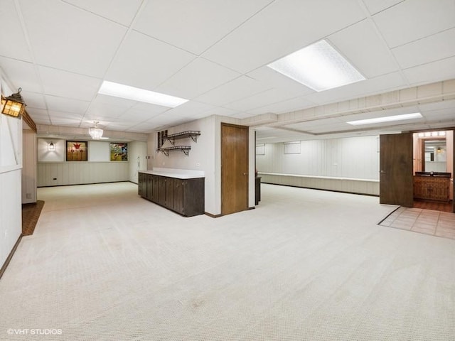 basement featuring light colored carpet and a paneled ceiling