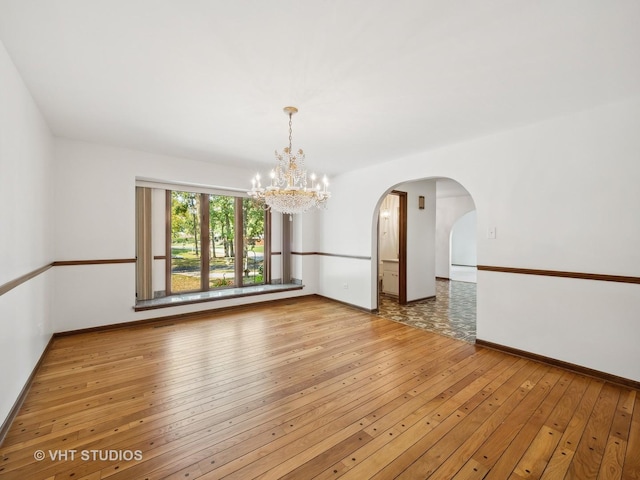 empty room with light hardwood / wood-style flooring and a chandelier