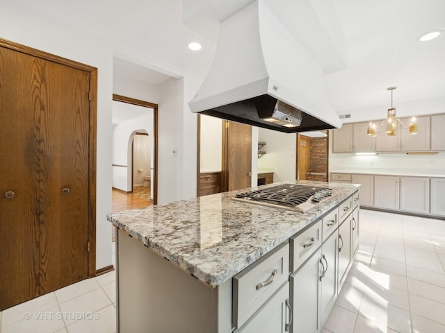 kitchen with a center island, exhaust hood, decorative light fixtures, stainless steel gas cooktop, and light tile patterned floors