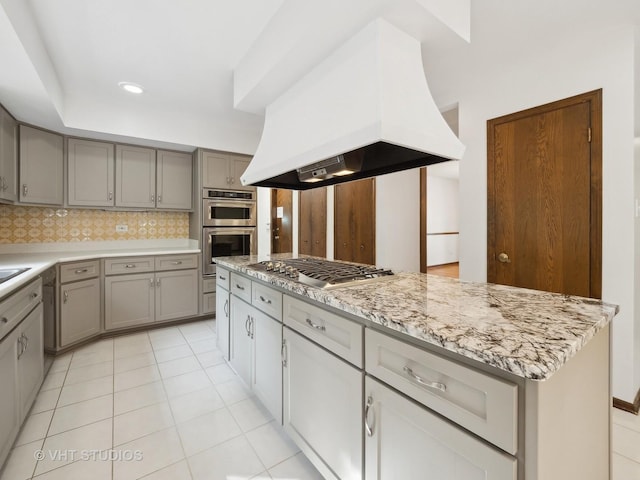 kitchen featuring stainless steel appliances, backsplash, gray cabinets, light tile patterned floors, and range hood