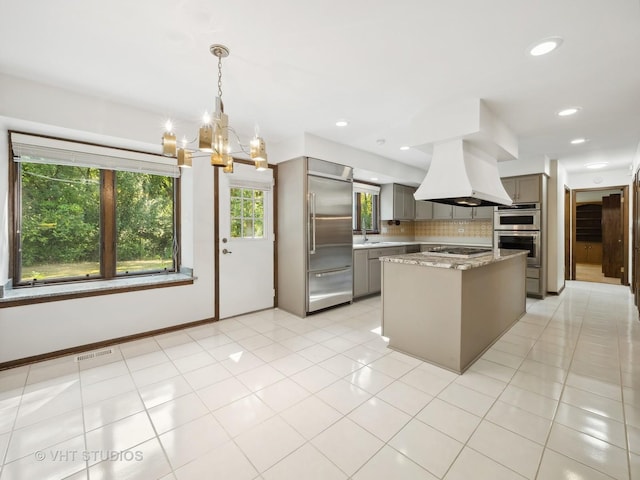 kitchen featuring pendant lighting, tasteful backsplash, light stone countertops, a center island, and stainless steel appliances