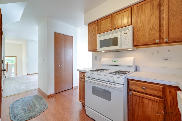 kitchen with white appliances and light hardwood / wood-style flooring