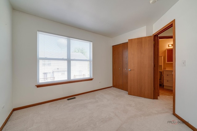 unfurnished bedroom featuring light colored carpet and a closet