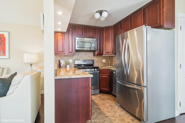 kitchen with light stone counters, sink, decorative backsplash, and appliances with stainless steel finishes