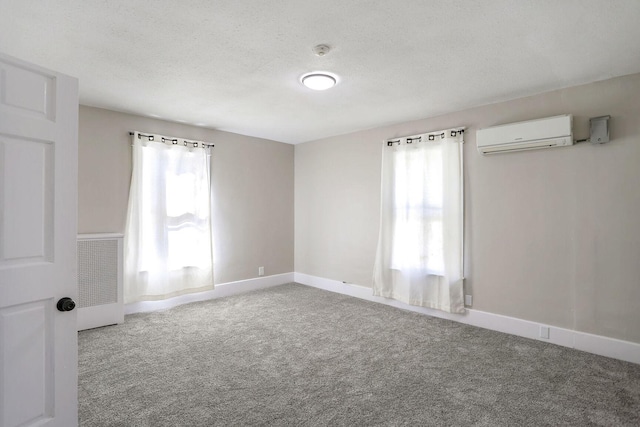 unfurnished room with a wall unit AC, a textured ceiling, and carpet flooring