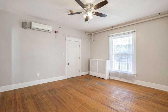 unfurnished room featuring wood-type flooring, radiator, ceiling fan, and a wall unit AC