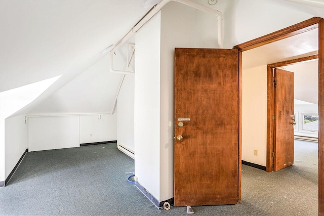 additional living space featuring baseboard heating, vaulted ceiling, and dark colored carpet