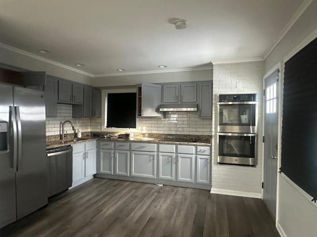 kitchen with sink, appliances with stainless steel finishes, dark hardwood / wood-style floors, gray cabinets, and decorative backsplash