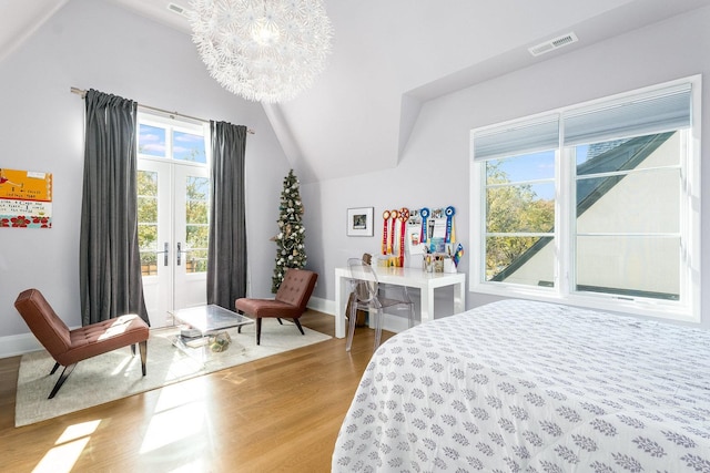 bedroom featuring hardwood / wood-style flooring, vaulted ceiling, a chandelier, and french doors