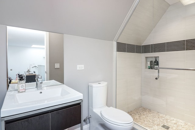 bathroom with vanity, lofted ceiling, tiled shower, and toilet