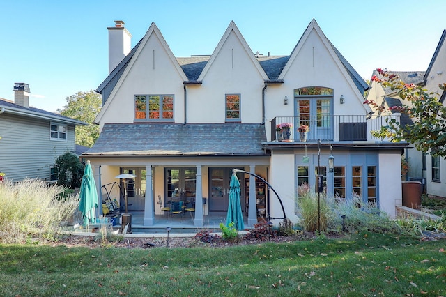 back of house with a yard, french doors, and a balcony