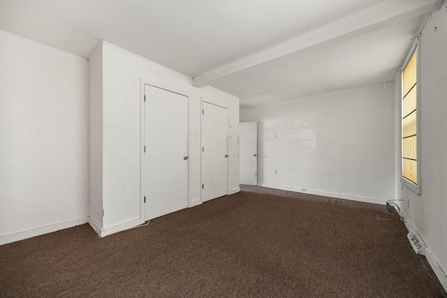 unfurnished bedroom featuring dark colored carpet and beam ceiling