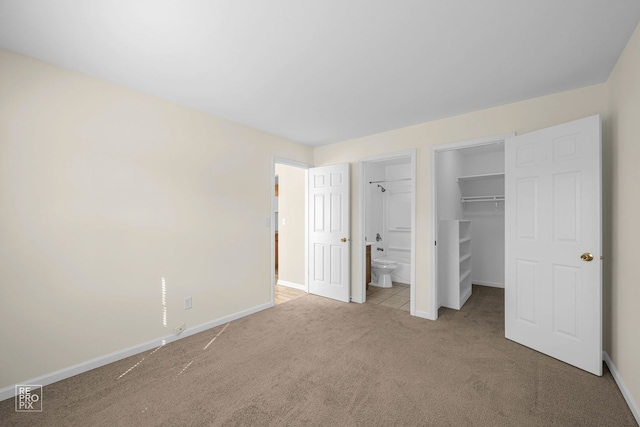 unfurnished bedroom featuring light carpet, a closet, and ensuite bath