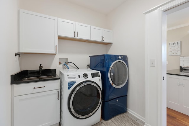 laundry room with sink, light hardwood / wood-style floors, cabinets, and washing machine and clothes dryer