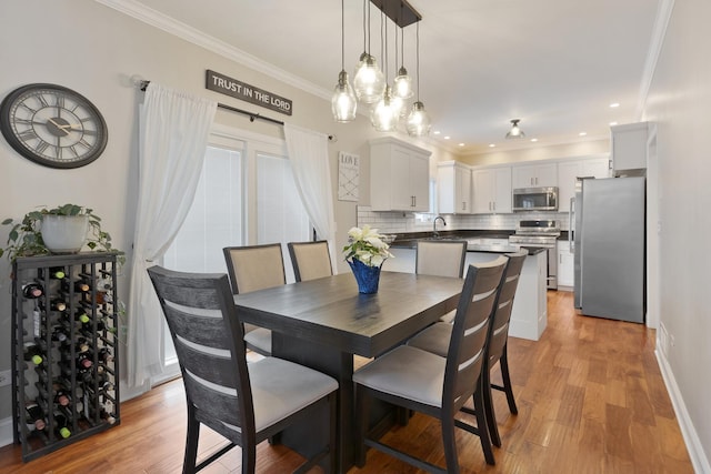 dining area with sink, crown molding, and light hardwood / wood-style flooring