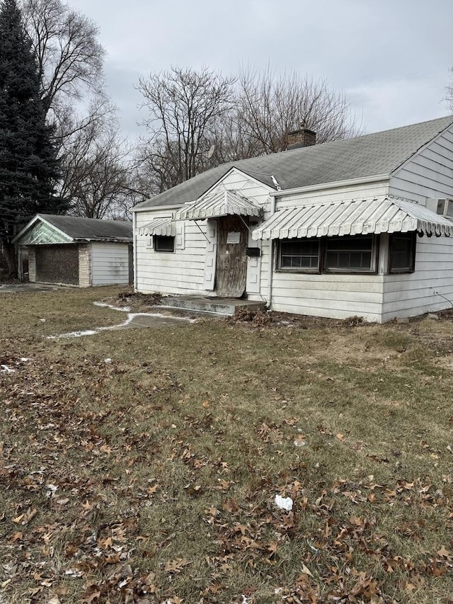 view of front facade with a garage, a front lawn, and an outdoor structure