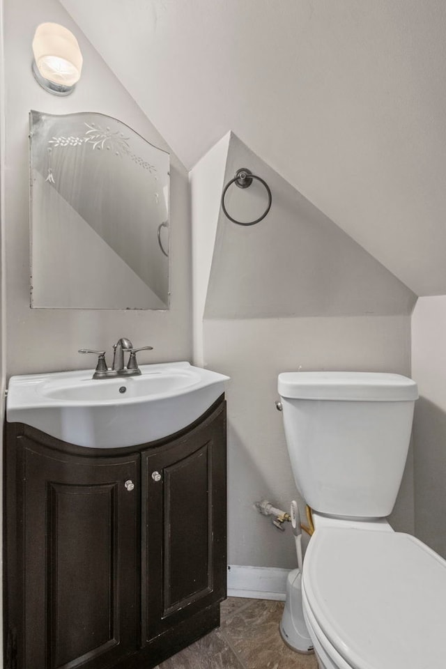 bathroom featuring vanity, toilet, and vaulted ceiling