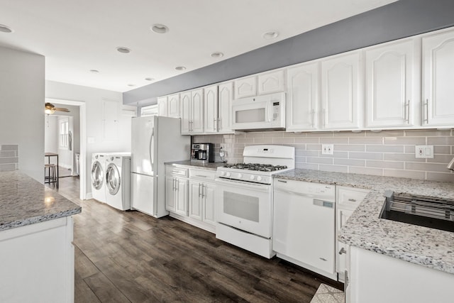 kitchen with white cabinetry, dark hardwood / wood-style flooring, white appliances, light stone countertops, and washer and clothes dryer