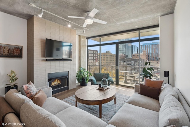 living room with hardwood / wood-style flooring, expansive windows, ceiling fan, and a fireplace