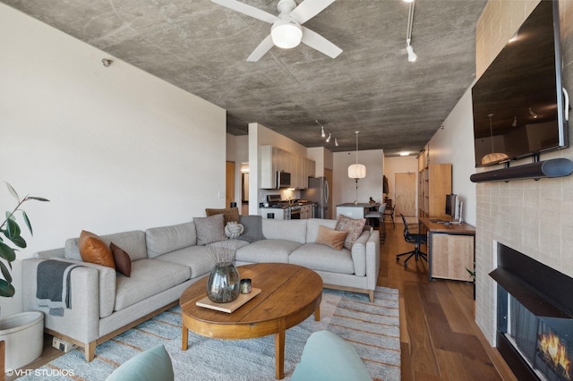 living room featuring a tile fireplace, hardwood / wood-style flooring, and ceiling fan