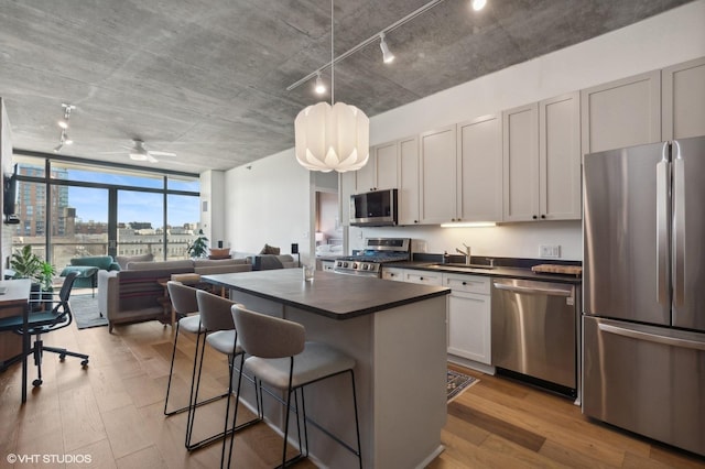 kitchen with light hardwood / wood-style floors, white cabinetry, stainless steel appliances, and a kitchen island