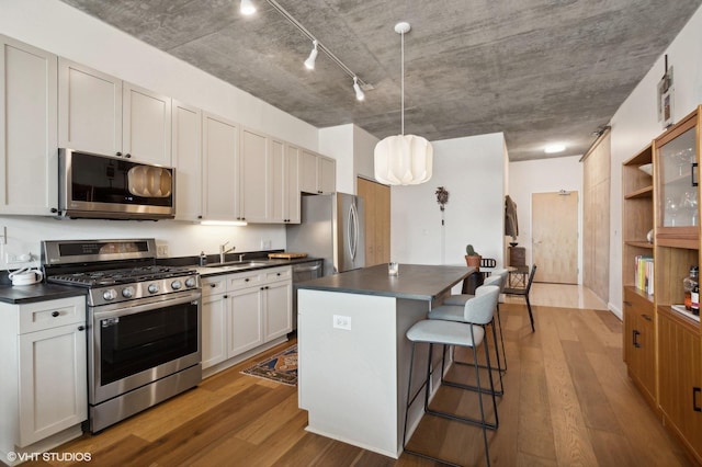 kitchen with a center island, hanging light fixtures, a kitchen breakfast bar, white cabinets, and stainless steel appliances