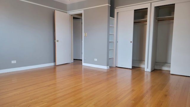 unfurnished bedroom featuring light hardwood / wood-style floors and two closets