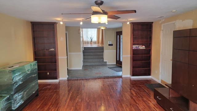 unfurnished living room featuring dark wood-type flooring and ceiling fan