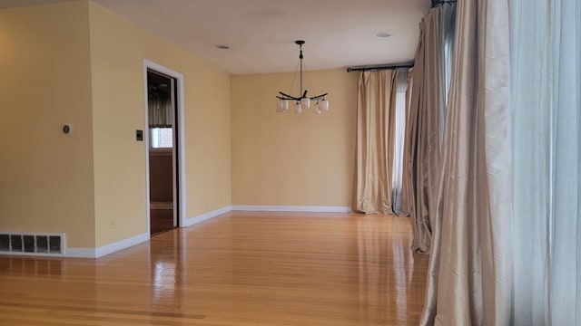 spare room with light hardwood / wood-style flooring and a notable chandelier