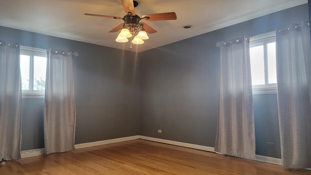 empty room featuring ceiling fan, a healthy amount of sunlight, and wood-type flooring