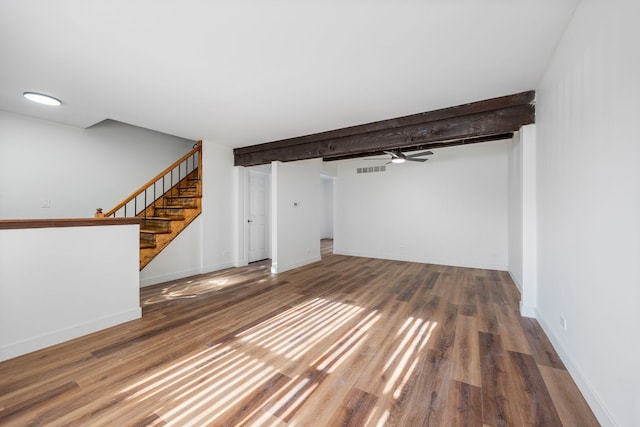 unfurnished living room with beamed ceiling and wood-type flooring