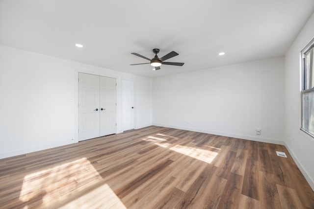 unfurnished bedroom featuring ceiling fan, dark hardwood / wood-style flooring, and two closets