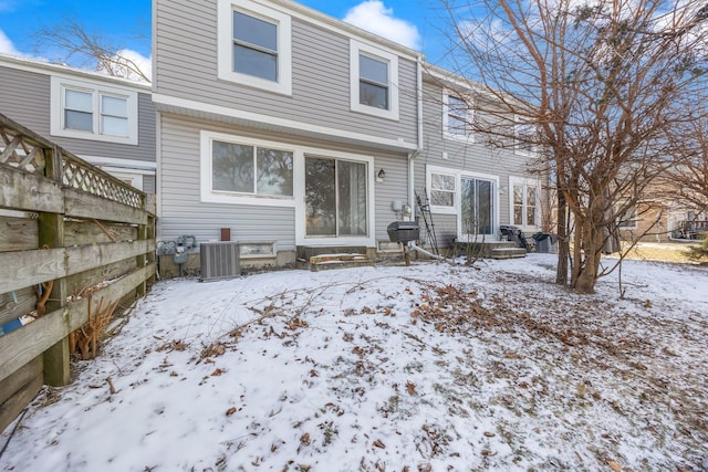 snow covered rear of property featuring central AC unit