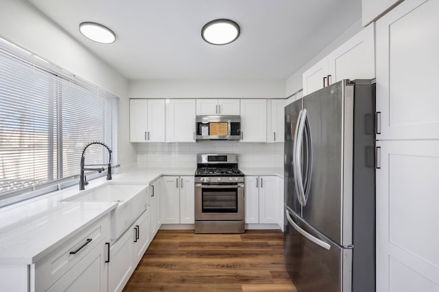 kitchen with backsplash, white cabinets, and appliances with stainless steel finishes