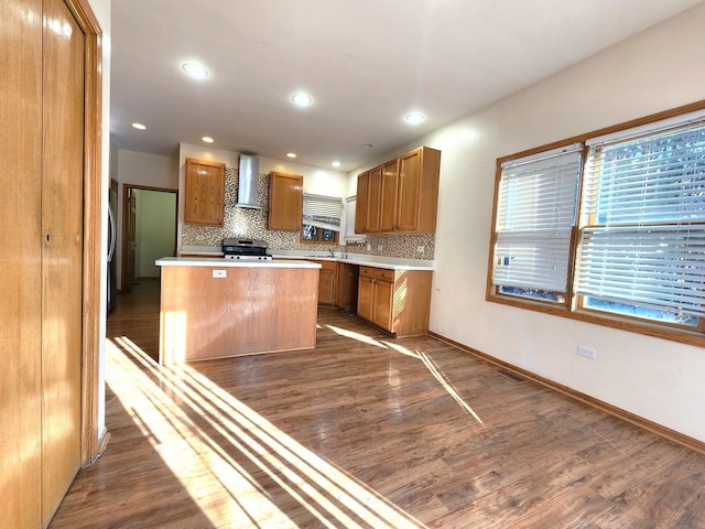 kitchen with dark wood-type flooring, tasteful backsplash, a center island, electric stove, and wall chimney range hood