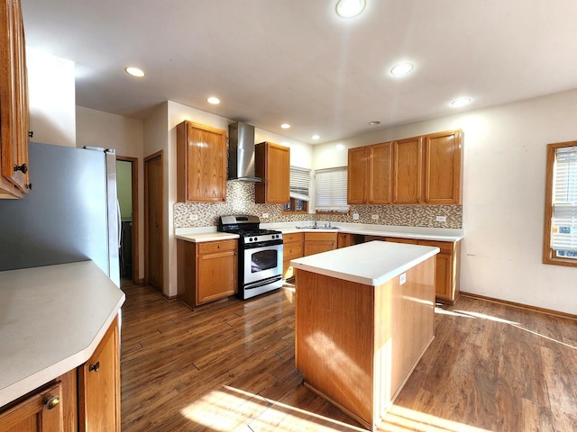 kitchen with a kitchen island, appliances with stainless steel finishes, sink, dark hardwood / wood-style flooring, and wall chimney exhaust hood