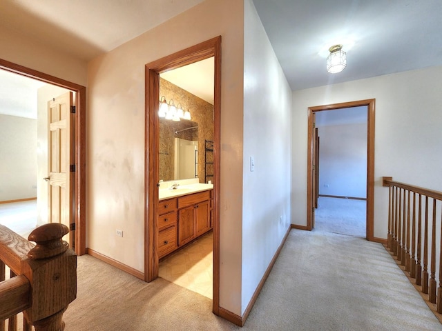 hallway with sink and light colored carpet