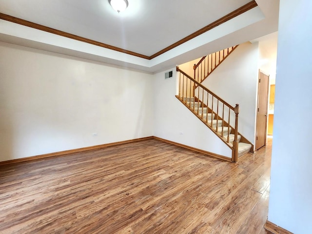 spare room featuring ornamental molding, wood-type flooring, and a tray ceiling