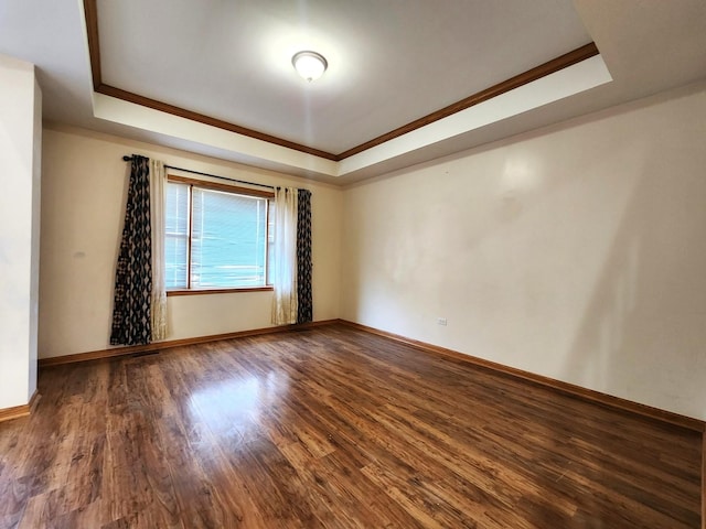 empty room with ornamental molding, wood-type flooring, and a tray ceiling