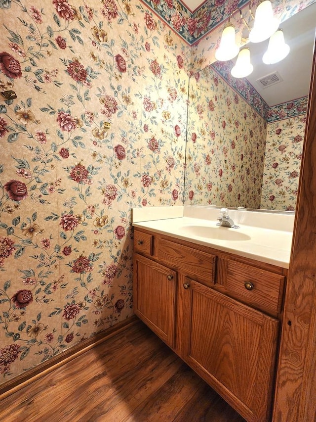 bathroom with an inviting chandelier, vanity, and hardwood / wood-style floors