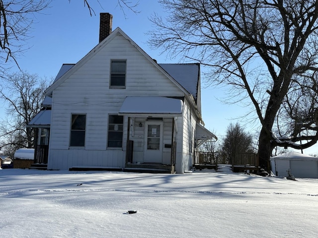 view of front of house featuring a chimney and an outdoor structure