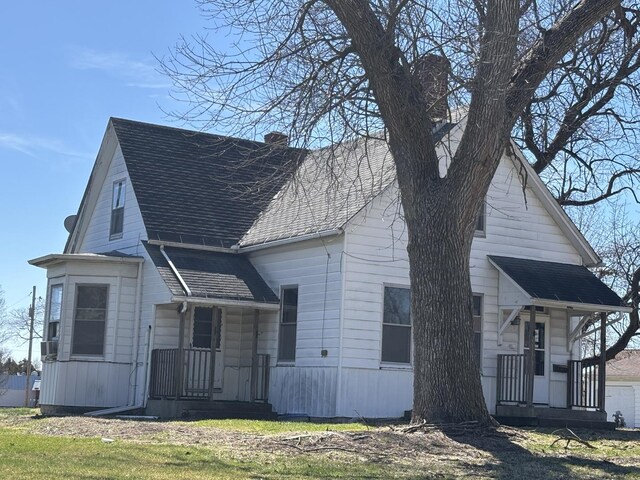view of front facade with a chimney and a shingled roof