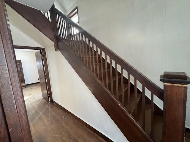 stairs featuring a decorative wall, a towering ceiling, and wood finished floors